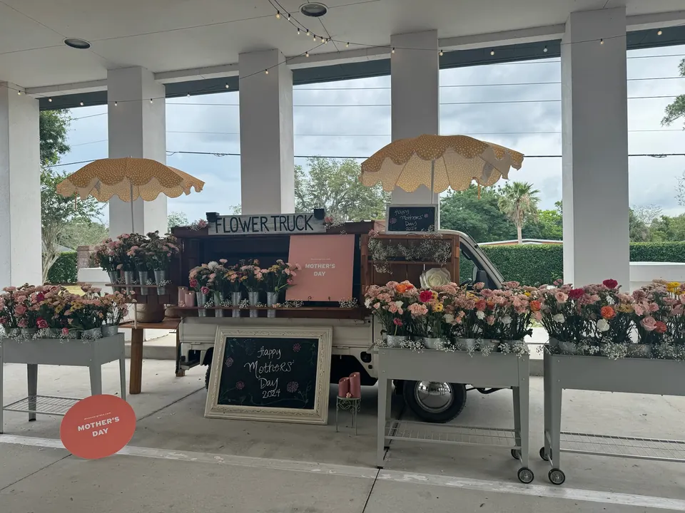 Expanded setup: flower carts of pink, coral and white blooms lined up on both sides of the flower truck under a covered entrance
