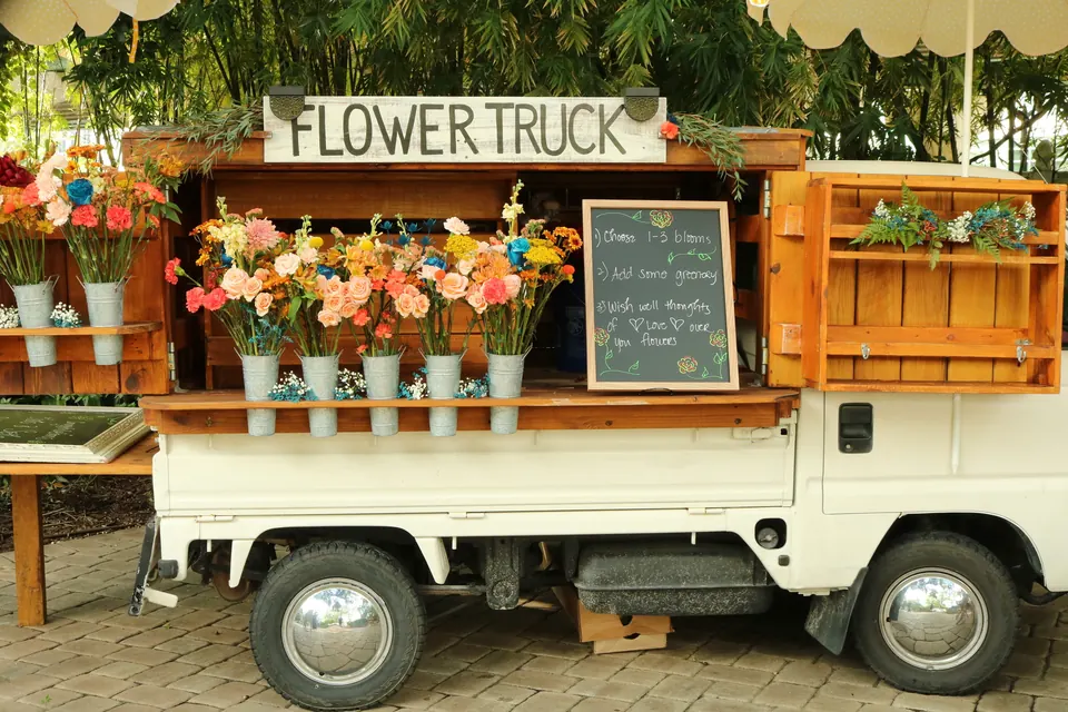 The flower truck in daylight with buckets of colorful bouquets and a chalkboard sign